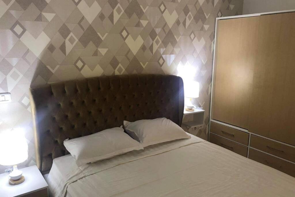 Luxury apartment at Jardin Carthage Tunis في تونس: غرفة نوم مع سرير مع اللوح الأمامي ومرآة
