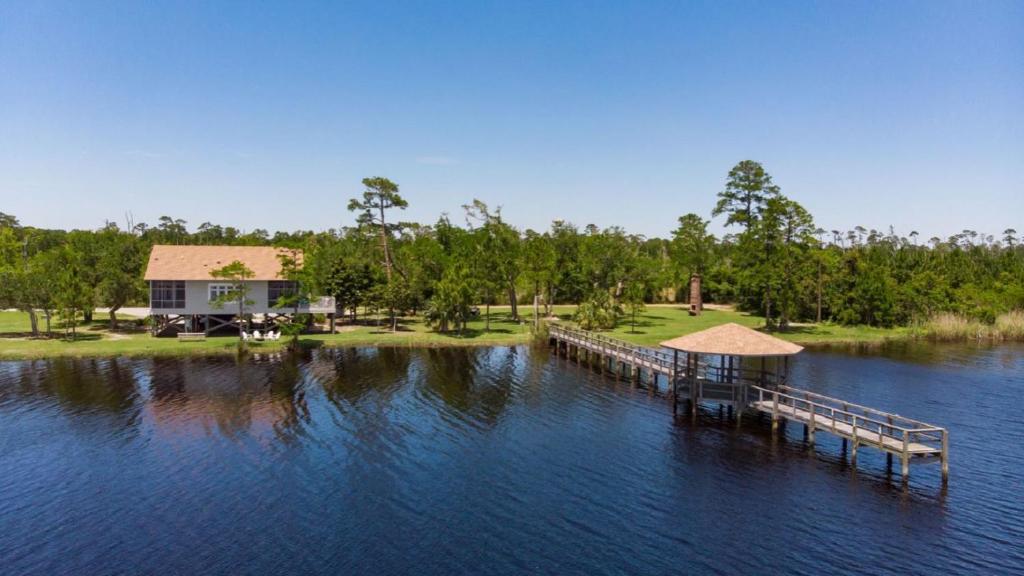 a dock in the middle of a lake with a house at Eagle Cottages at Gulf State Park in Gulf Shores