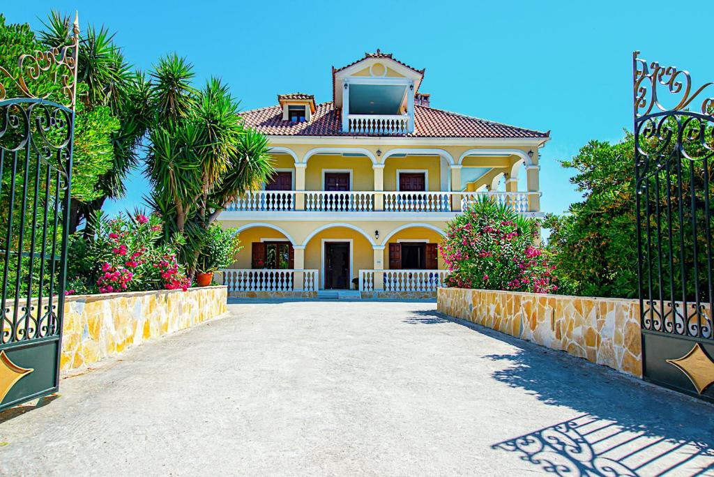 een groot geel huis met een hek ervoor bij La Maison di Angelo Apartment Zakynthos Island in Áyios Kírikos