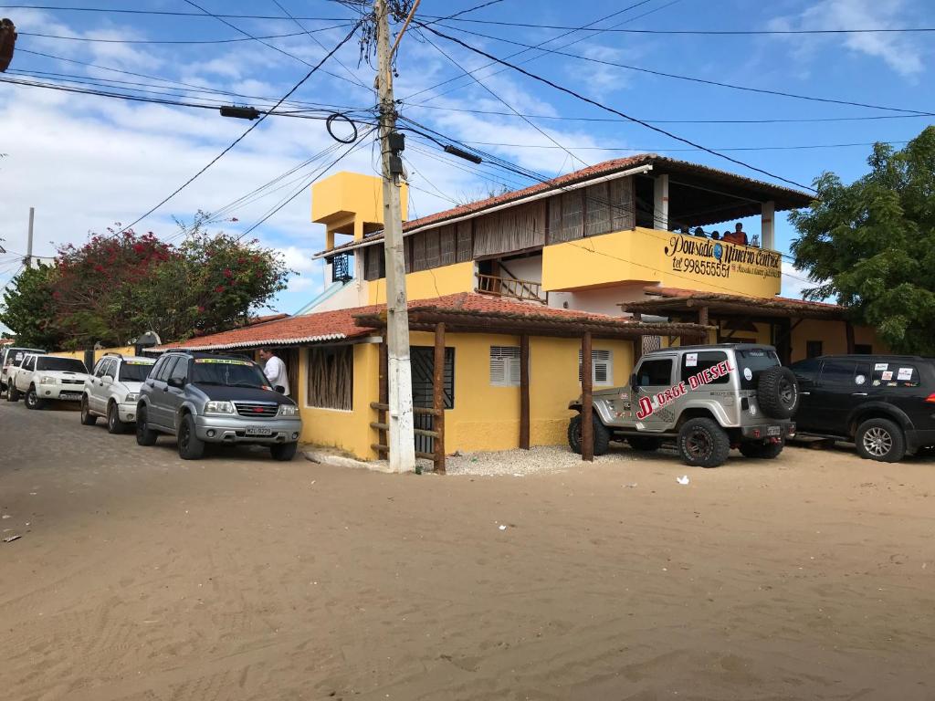 a yellow building with cars parked in front of it at Pousada o Mineiro Central in Galinhos