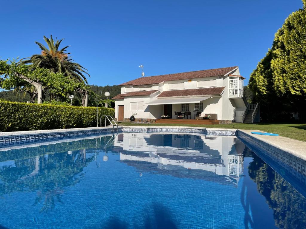 a large swimming pool in front of a house at Tranquilidad con piscina en Casa Nantes en Sanxenxo in Sanxenxo