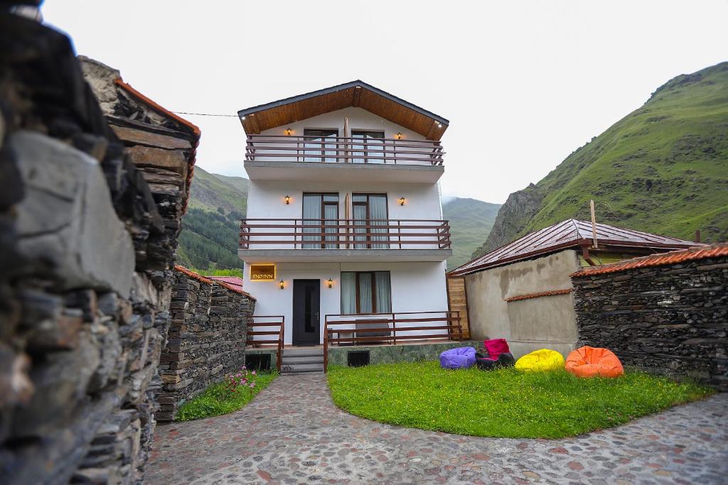 a white building with a balcony on top of it at Sno Inn Kazbegi in Stepantsminda