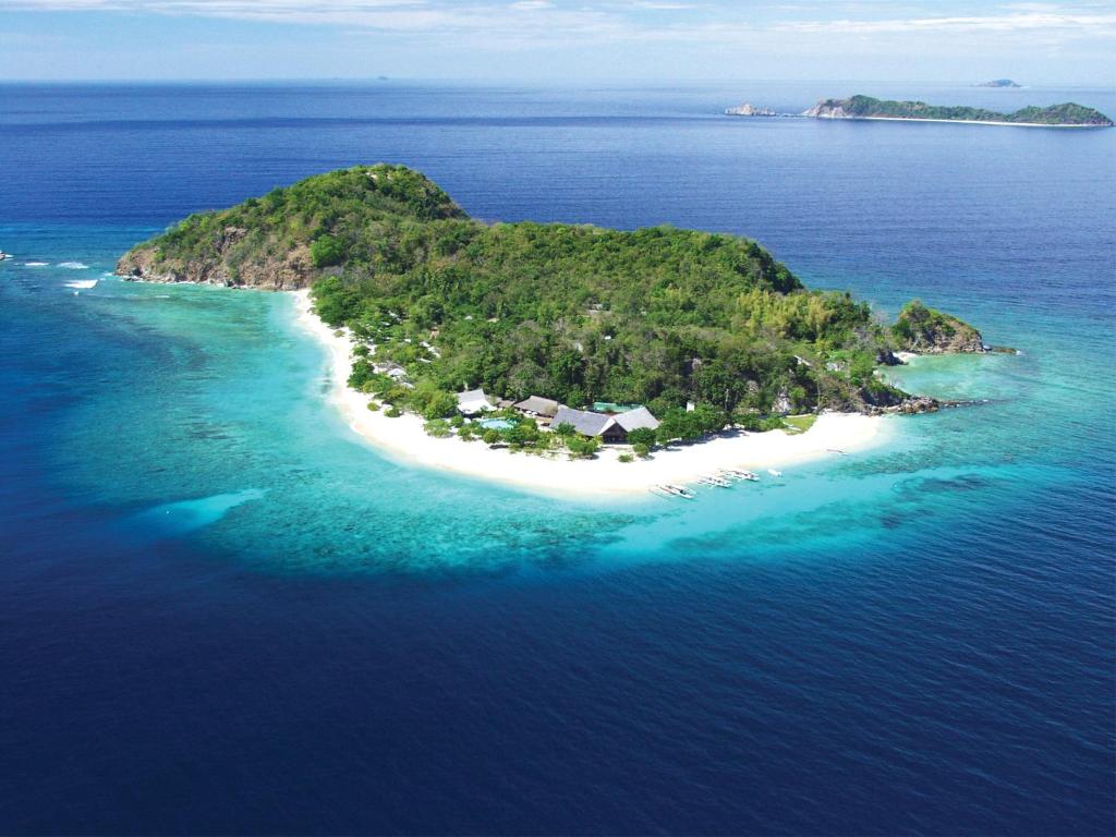 an island in the ocean with a house on it at Club Paradise Palawan in Coron