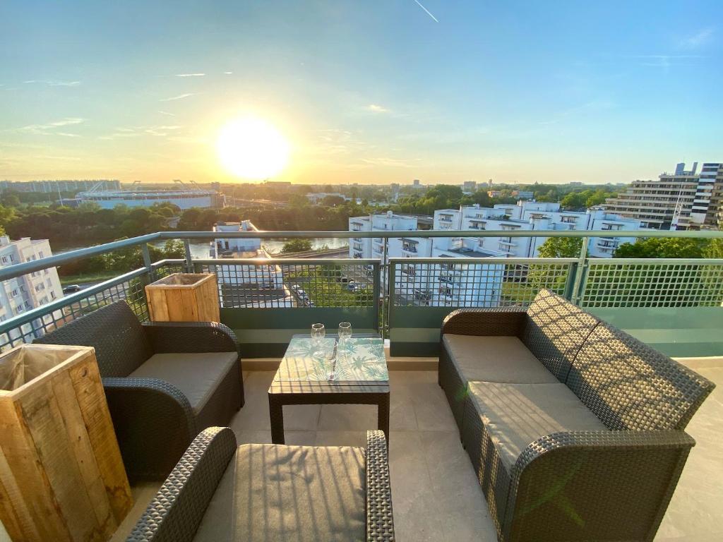a balcony with couches and a table with a sunset at Evasion dépaysante en bord de Garonne in Toulouse
