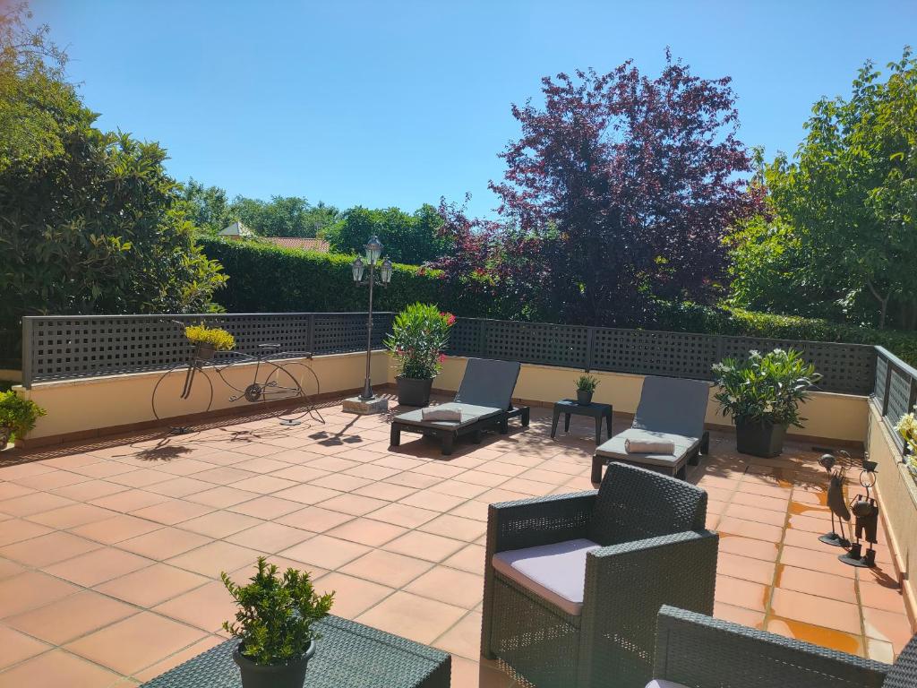 d'une terrasse avec des chaises, des tables et une clôture. dans l'établissement Loft Abantos - 120m2 más Terraza y Jardín Independiente, à San Lorenzo de El Escorial