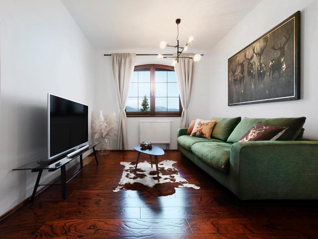sala de estar con sofá verde y TV en TatryView Apartments by KingDubaj, en Veľká Lomnica