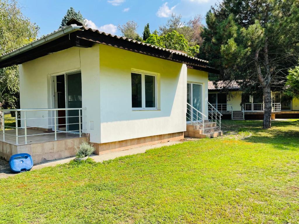 une petite maison jaune et blanche avec une cour dans l'établissement Fuk-tak's bungalow, à Dojran