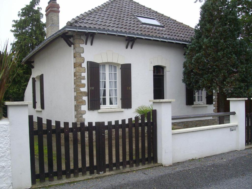 a small white house with a black fence at maison à 400 mètres de la plage in La Baule