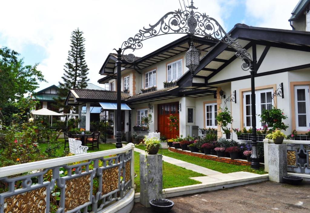 a white house with a gate and a fence at Cocoon Hills in Nuwara Eliya