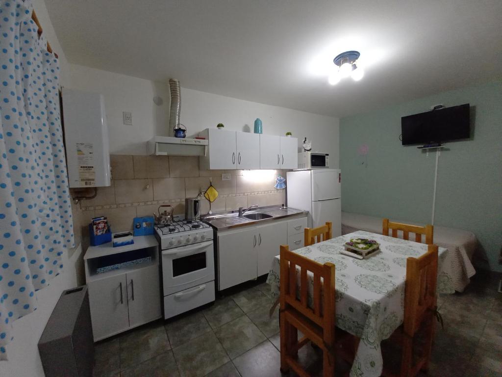 uma pequena cozinha com uma mesa, um fogão, uma mesa e cadeiras em Departamentos Buen Pasar em Ushuaia