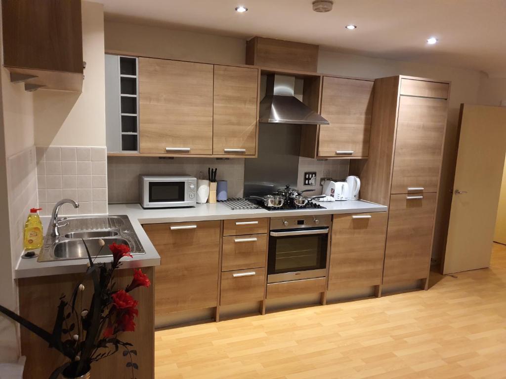 a kitchen with wooden cabinets and a sink and a microwave at Vetrelax Colchester Apartment in Colchester