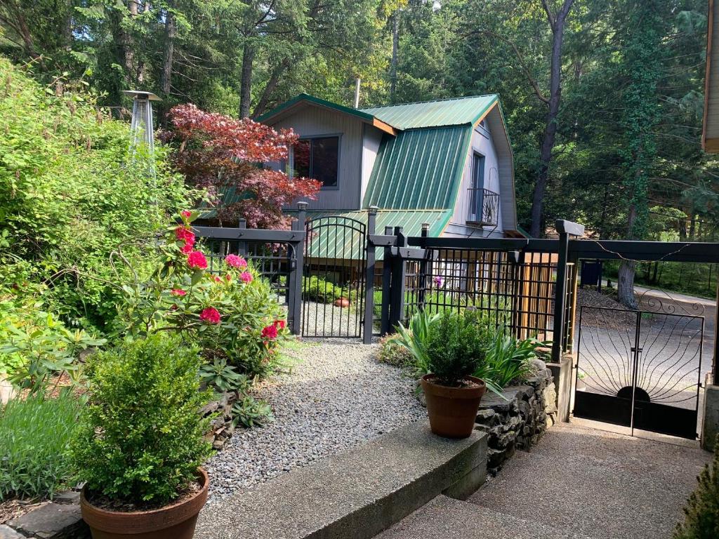 a gate to a garden with plants and a house at Salt Spring Carriage House B&B in Ganges