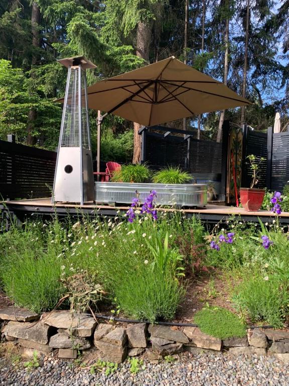 a garden with an umbrella and some flowers at Salt Spring Carriage House B&B in Ganges