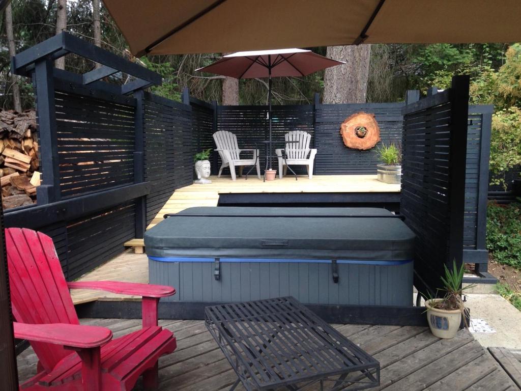 a patio with a hot tub and two chairs and an umbrella at Salt Spring Carriage House B&B in Ganges