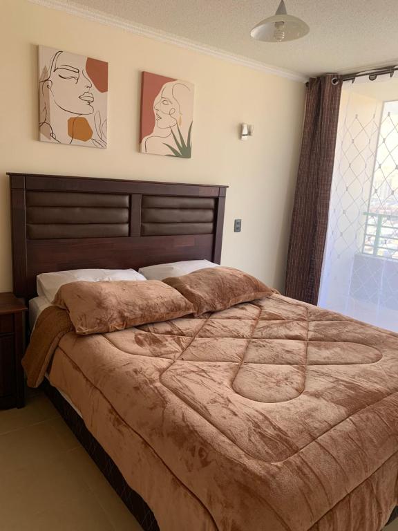 a bedroom with a large bed and two pictures on the wall at Magnolia apart Con facturas in Iquique