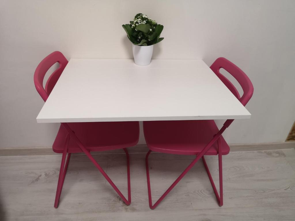 une table blanche avec deux chaises rouges et une plante en pot dans l'établissement Monolocale Studio Flat, à Pérouse