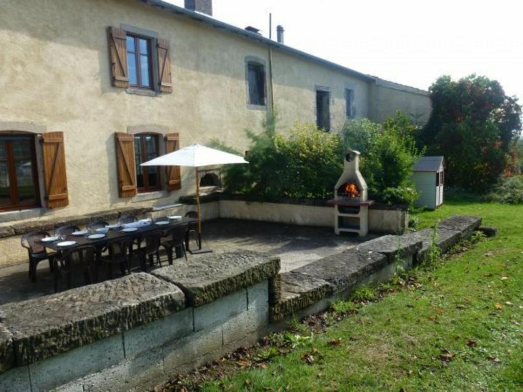 eine Außenterrasse mit Tischen, einem Sonnenschirm und einem Grill in der Unterkunft Gîte Serocourt, 5 pièces, 9 personnes - FR-1-589-219 in Serocourt