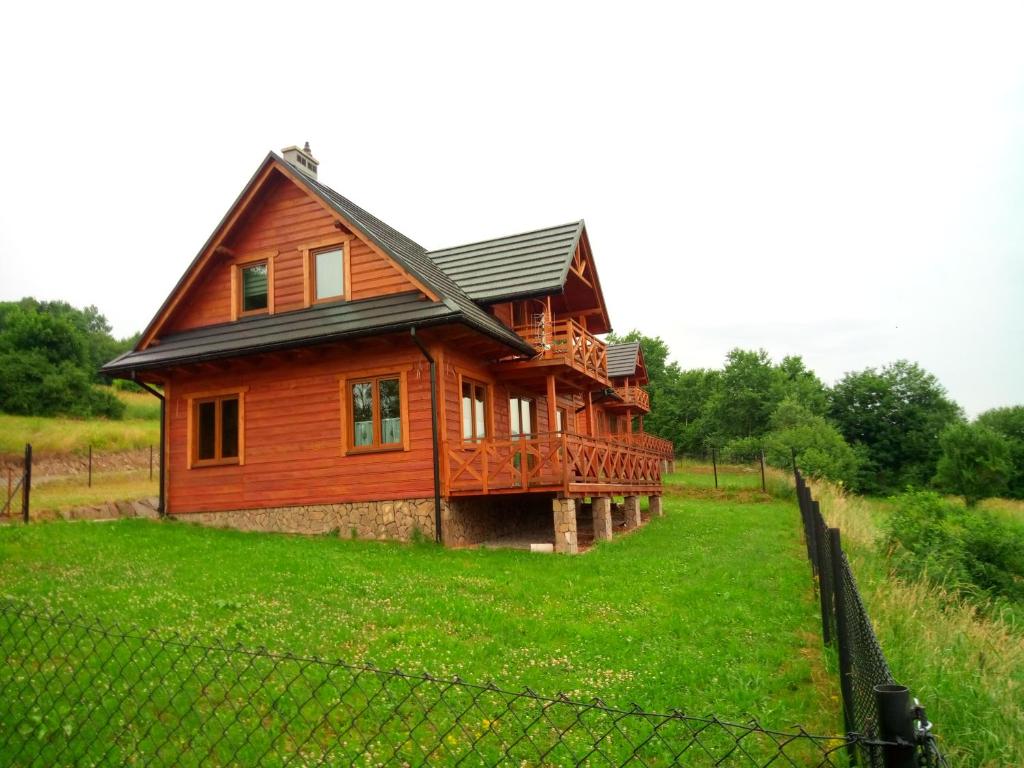 a wooden house on a green field with a fence at Dom Słoneczna Chata Kasina Wielka in Kasina Wielka
