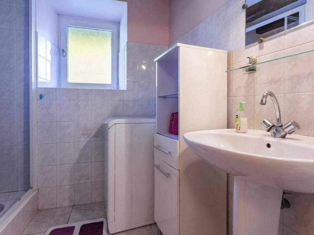 ein weißes Bad mit einem Waschbecken und einer Dusche in der Unterkunft Gîte Saint-Lyphard, 3 pièces, 4 personnes - FR-1-306-1132 in Saint-Lyphard