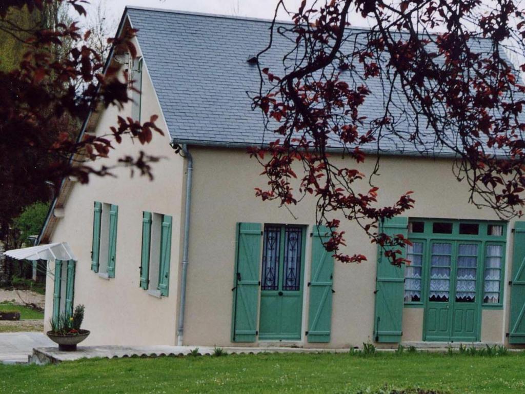 ein Haus mit grünen und weißen Türen und einem Baum in der Unterkunft Gîte Martizay, 3 pièces, 4 personnes - FR-1-591-67 in Martizay