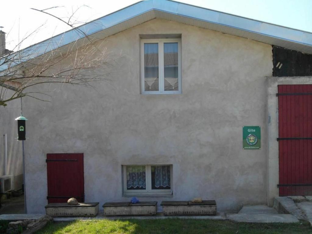 uma casa com duas portas vermelhas e um cão deitado na frente em Gîte Laître-sous-Amance, 2 pièces, 3 personnes - FR-1-584-68 