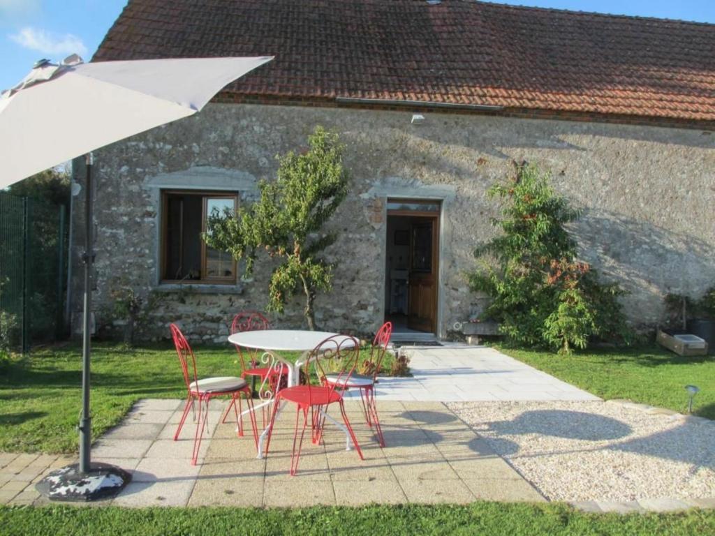 une table, des chaises et un parasol en face d'une maison dans l'établissement Gîte Guilly, 2 pièces, 2 personnes - FR-1-590-30, à Guilly