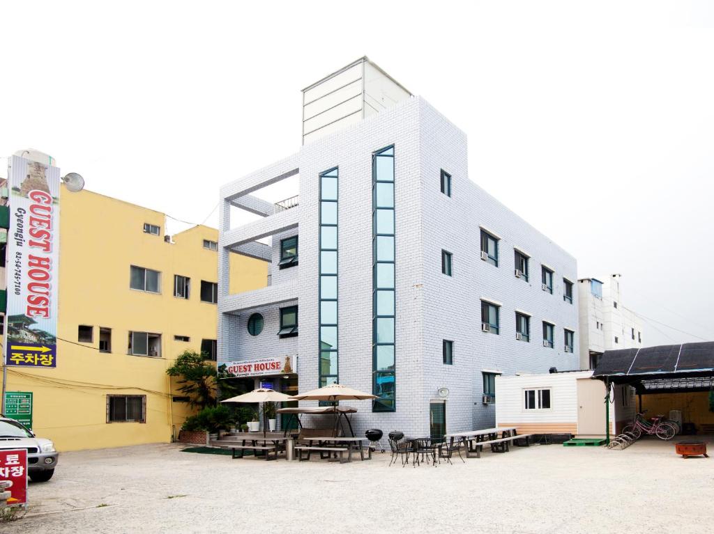 a building with tables and umbrellas in a parking lot at Gyeongju Guesthouse in Gyeongju