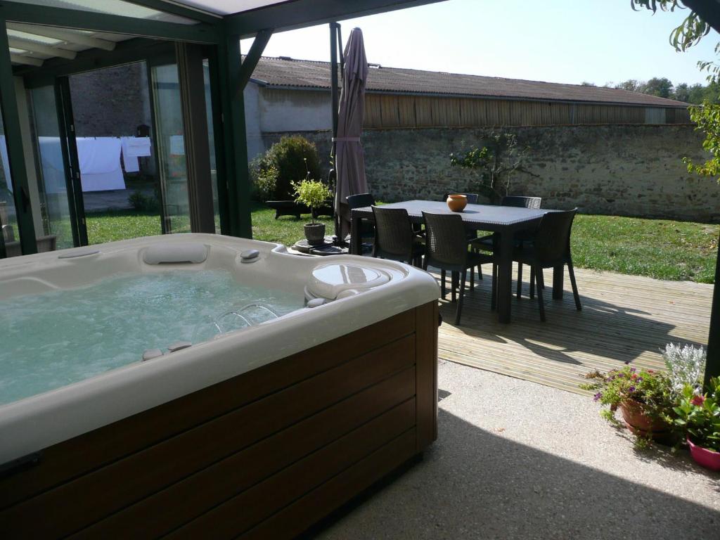 a jacuzzi tub in a backyard with a table at Maison de Charme avec Spa et Véranda - Proche Thermes de Vittel et Cité des Images - FR-1-589-252 in Velotte-et-Tatignécourt