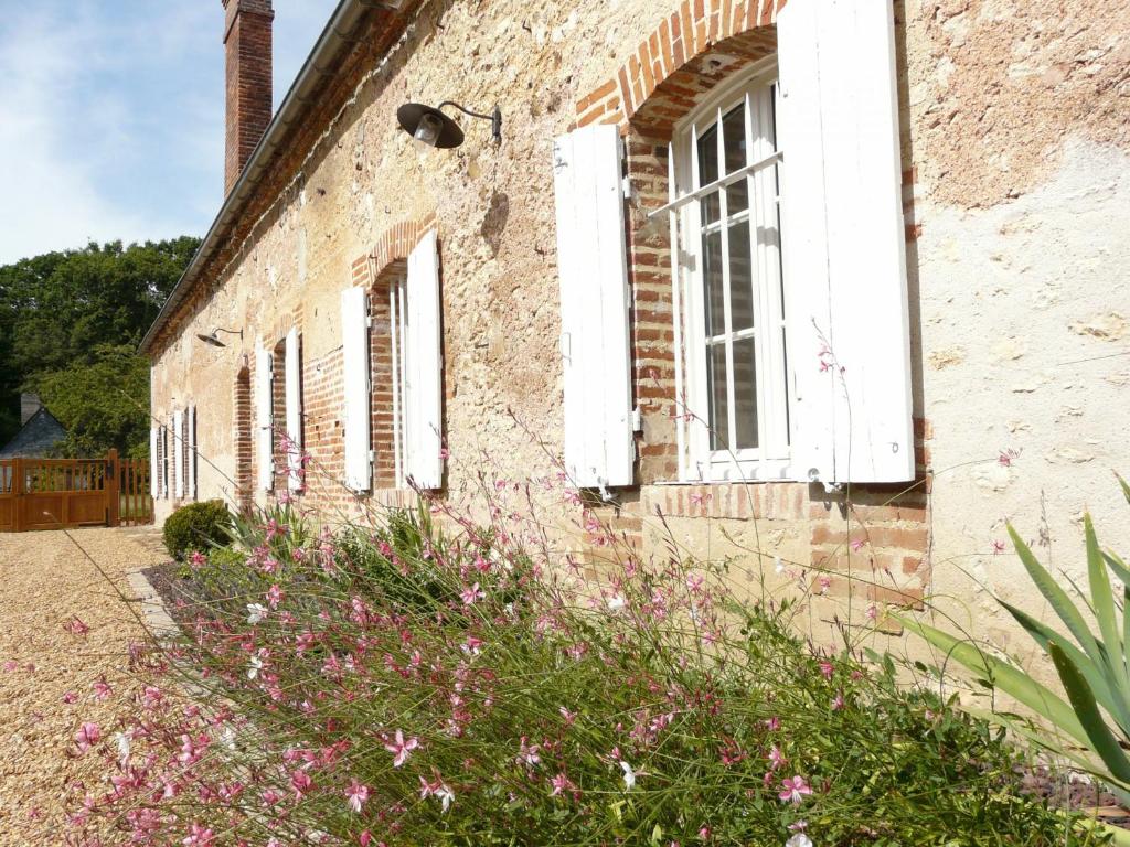 um antigo edifício de tijolos com janelas brancas e flores cor-de-rosa em Gîte Les-Villages-Vovéens, 5 pièces, 12 personnes - FR-1-581-63 