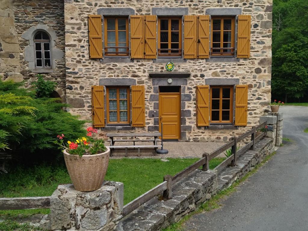 um edifício de pedra com persianas amarelas e um vaso com flores em Gîte Saint-Didier-sur-Doulon, 5 pièces, 8 personnes - FR-1-582-222 em Saint-Didier-sur-Doulon