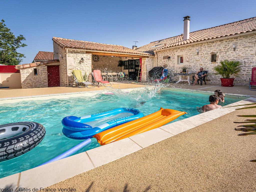 a boy is playing in a swimming pool with a slide at Gîte L'Hermenault, 8 pièces, 14 personnes - FR-1-426-362 in LʼHermenault