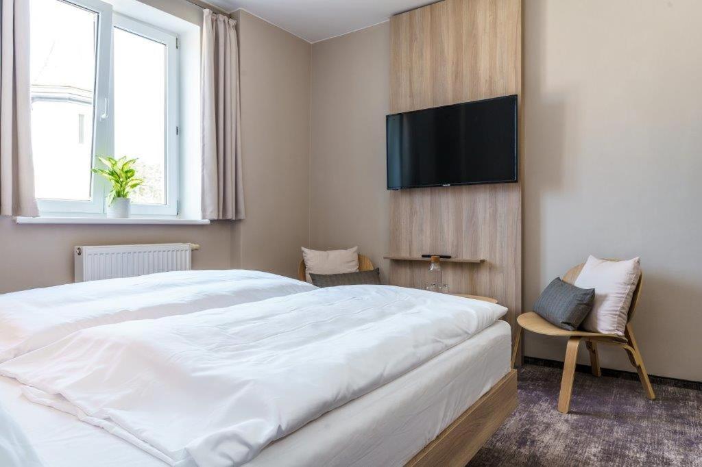 sypialnia z dużym białym łóżkiem i telewizorem z płaskim ekranem w obiekcie Hotel Jitřenka w mieście Konstantinovy Lázně