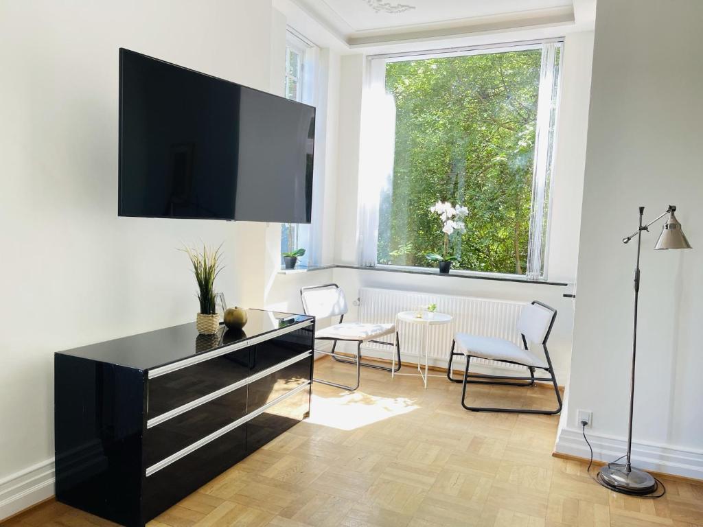 ein Wohnzimmer mit einem Flachbild-TV an der Wand in der Unterkunft aday - Aalborg mansion - Open bright apartment with garden in Aalborg