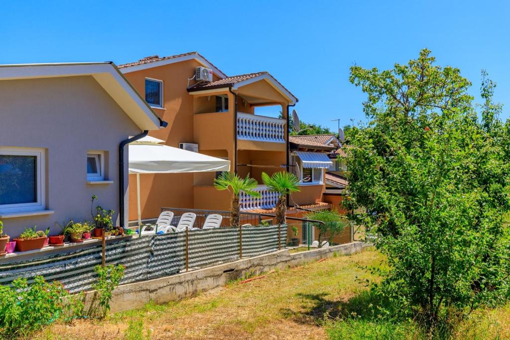 ein Haus mit einer Terrasse mit Stühlen und einem Sonnenschirm in der Unterkunft Apartments Vanessa with Shared Pool in Nova Vas