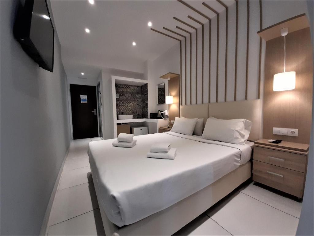 a bedroom with a large white bed and a television at Elite Hotel in Rhodes Town