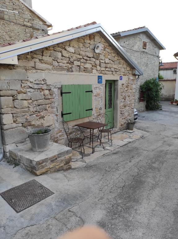 a stone building with a green door and two chairs at Ema in Buzet