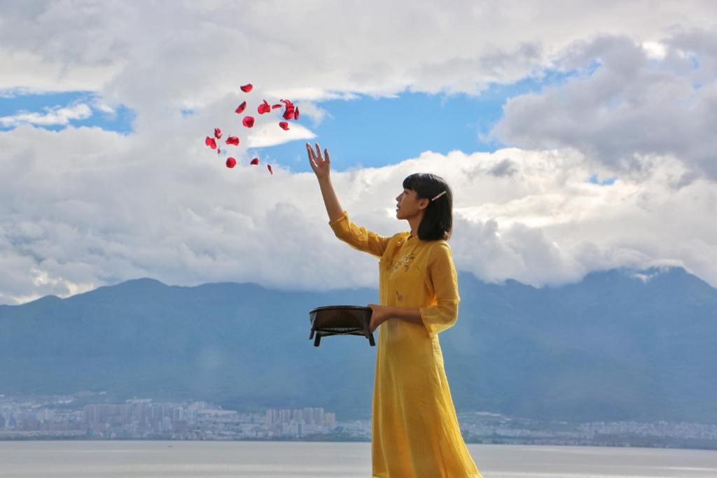大理市にあるDali Liao Fan Seaview Villaの黄色い服を着た女が凧を飛んでいる