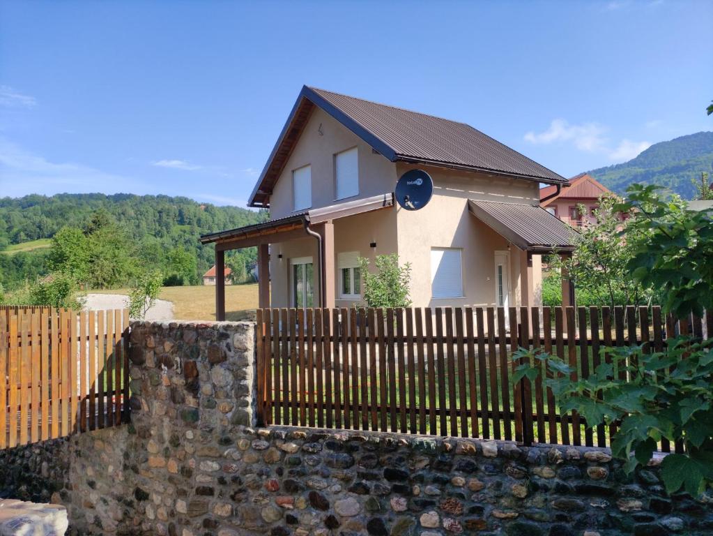 a house with a wooden fence and a stone wall at Bajka in Kolašin