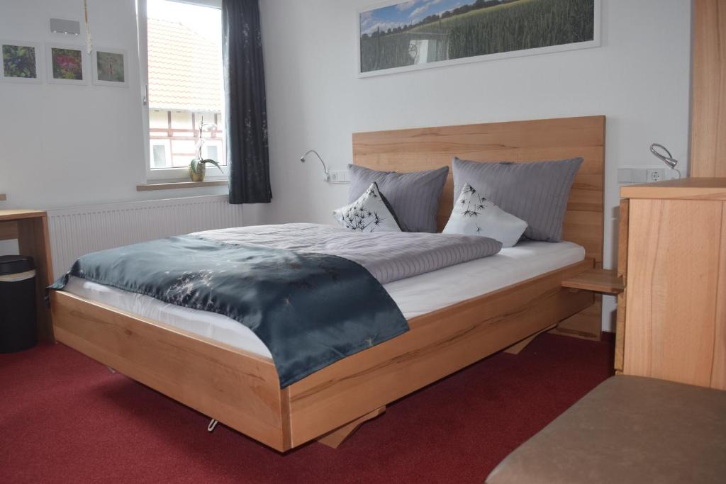 een slaapkamer met een groot bed met een houten hoofdeinde bij HOTEL BIKE & HIKE in Obersuhl