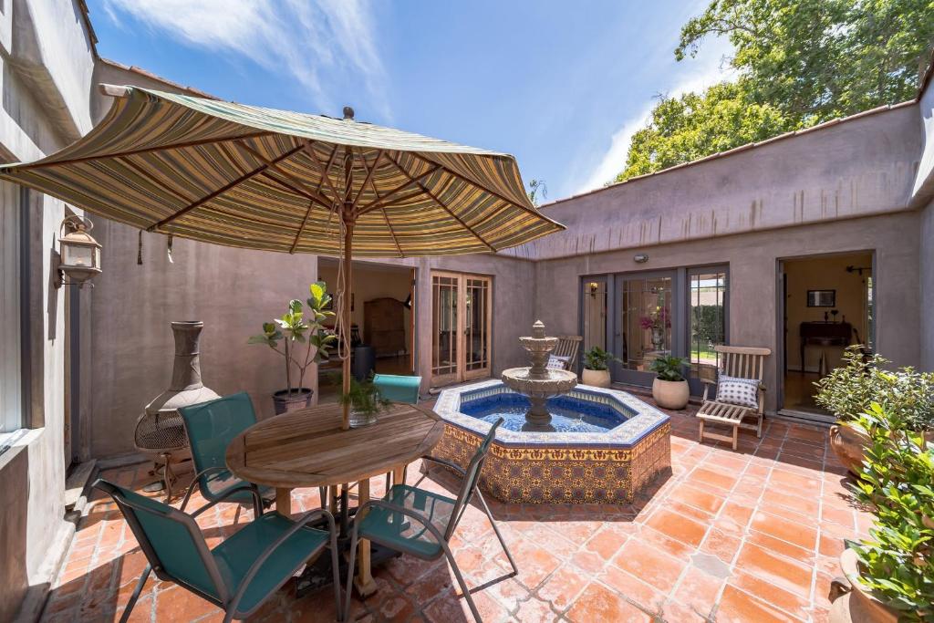 a patio with a table and an umbrella and a fountain at 1925 Spanish Villa Retreat near Disneyland in Historic Park Santiago home in Santa Ana