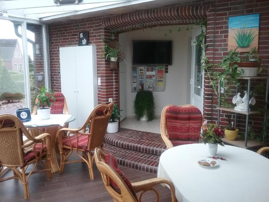 patio con mesas y sillas y TV en Grosszügige Wohnung für 4 Personen in Ostfriesland mit E- Ladesäule, en Utarp