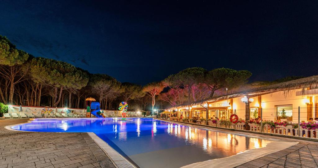 una piscina notturna con un resort di Arcobaleno Village a Marina di Bibbona