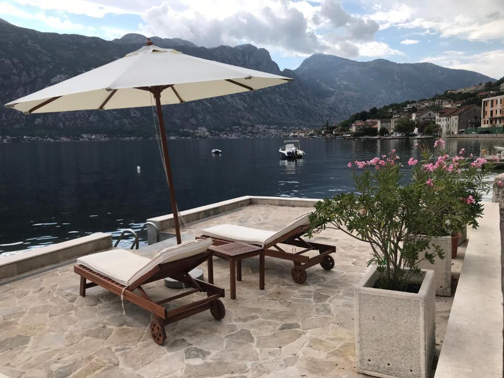 a patio with a table and two chairs and an umbrella at AMAZING SEA VIEW Guest House ADRIATICA in Kotor