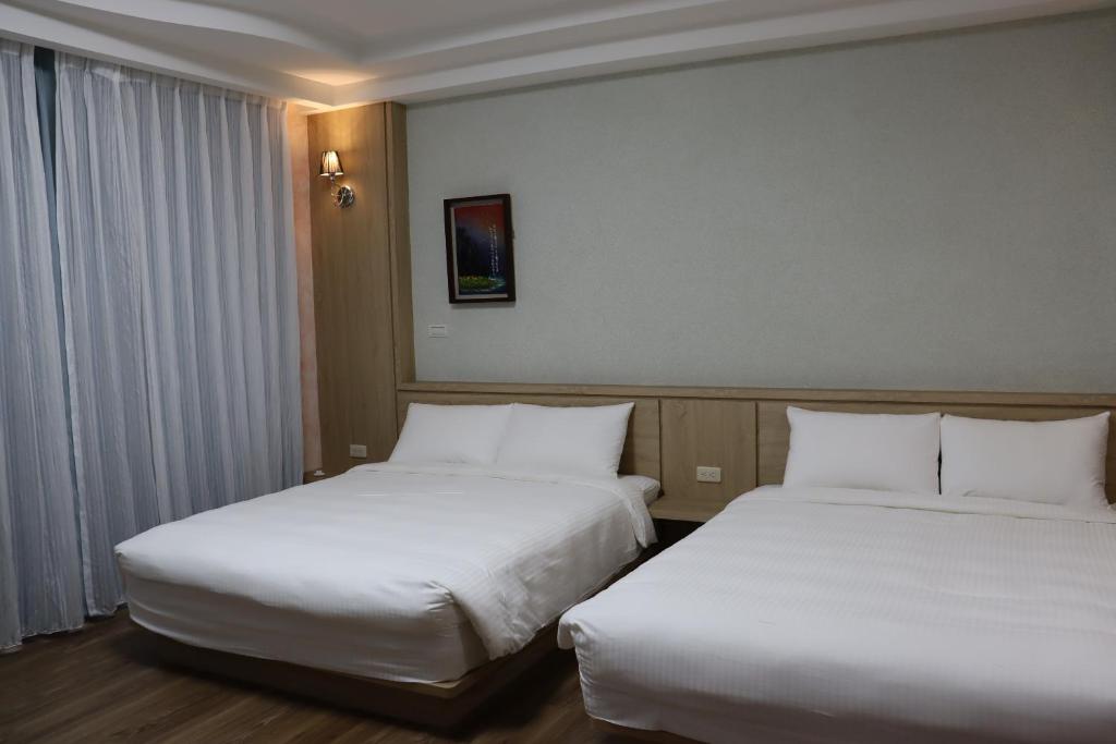 2 łóżka w pokoju hotelowym z białą pościelą w obiekcie 天強民宿 w mieście Magong