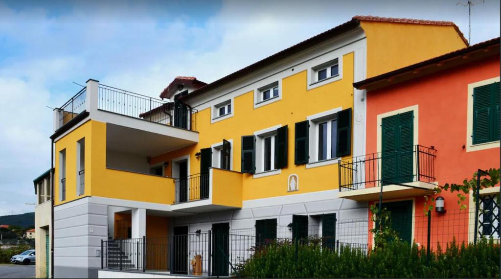 un edificio giallo e bianco con porte verdi di Casa di Claudia ad Arnasco