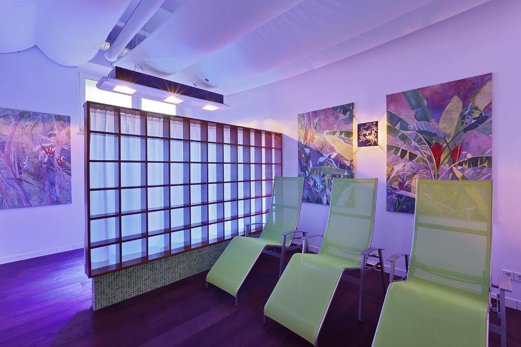 a room with green chairs and paintings on the walls at At the Park Hotel in Baden