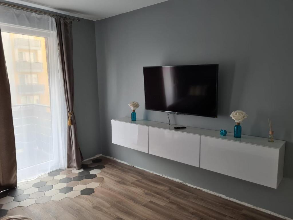 een woonkamer met een flatscreen-tv op een witte kast bij Garsoniera Zebra in Braşov