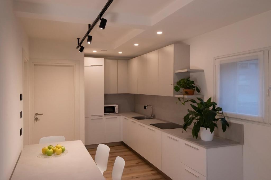 a kitchen with white cabinets and a table with fruit on it at SILVANELLO Apartment in Trento