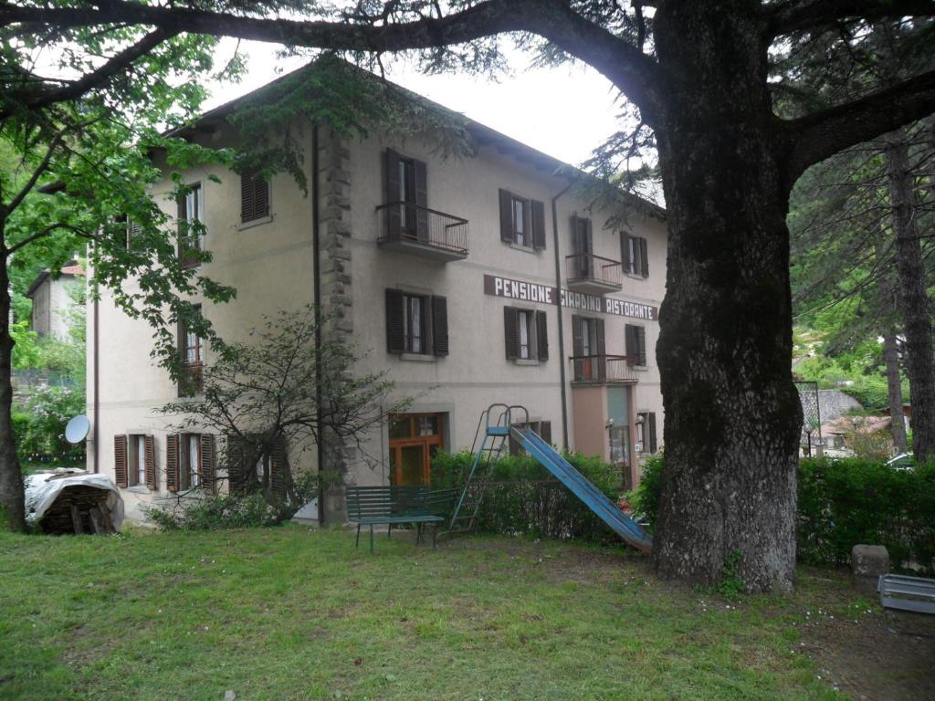 a house that has a tree in front of it at Albergo Giardino in Badia Prataglia