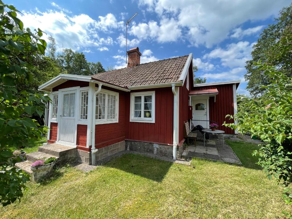 una pequeña casa roja con un patio de césped en Skruvshultkvarn, en Berga